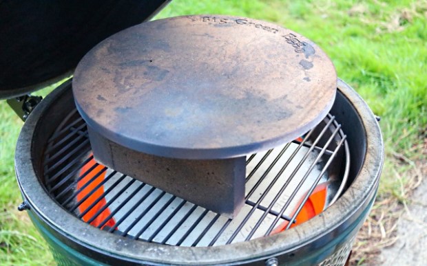 Big Green Egg set up to cook thin crust pizza. Fire bricks raise the stone.