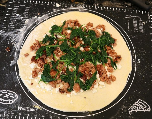 Pizza rolled out on a sizing mat and toppings added