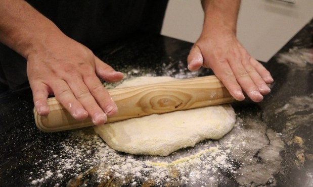 Rolling the dough on a surface with polenta and flour