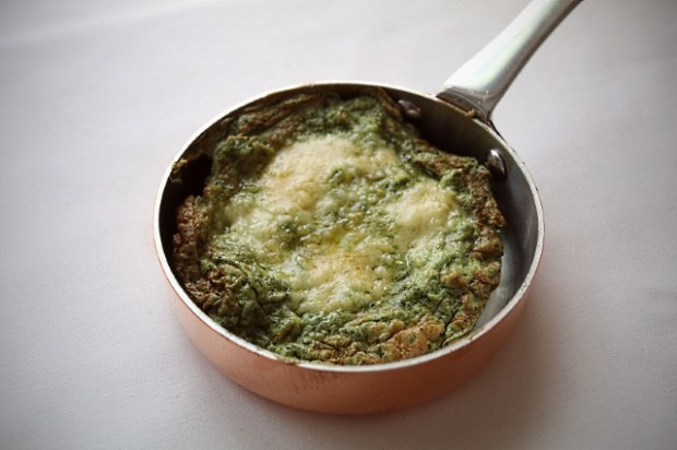 Single serving of green egg omelette in a copper pan