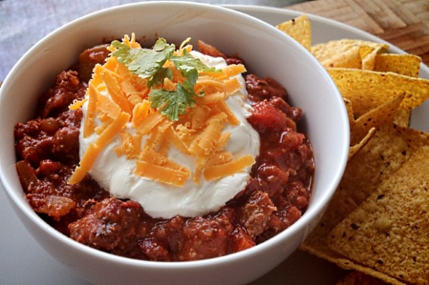 Over the top smoked chili with sour cream, cheese, coriander and tortilla chips