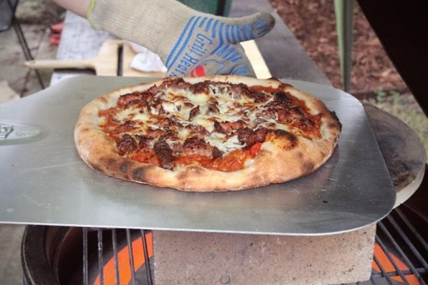 Using heat resistant gloves to remove the pizza