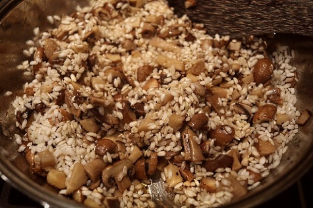 Stirring chicken stock into the mushrooms and risotto rice