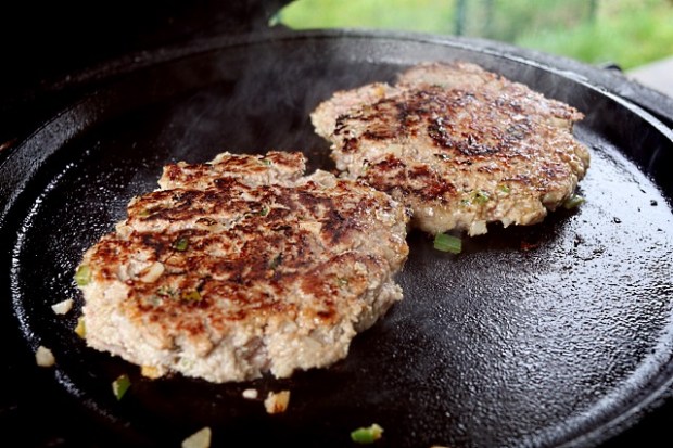 Flattened burgers browning off on the cast iron surface