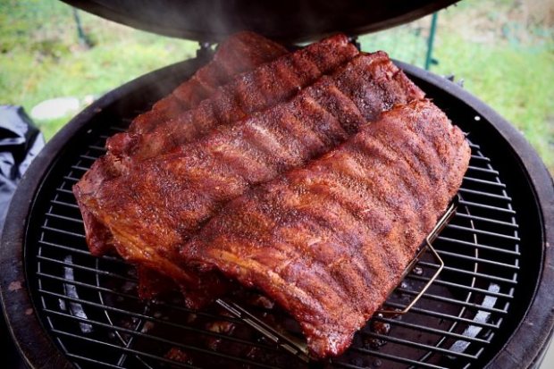 Baby back ribs smoking in a rib rack