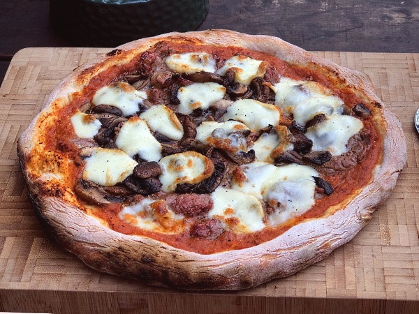 Steak and mushroom pizza ready to be sliced and served