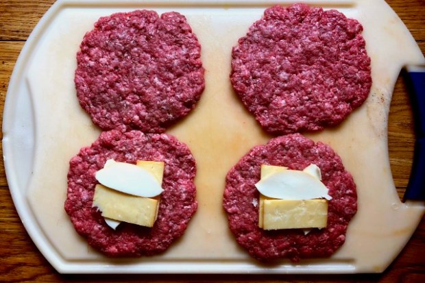 Four burger patties with cheese layered on two of them