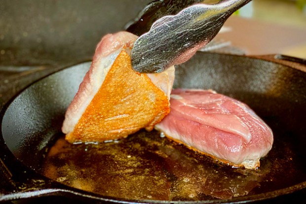 Checking that the skin is crisp before adding mushrooms