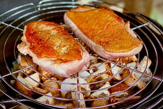 Duck breast cooking over mushrooms